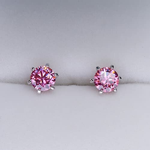 Pink gemstone stud earrings on a soft surface.